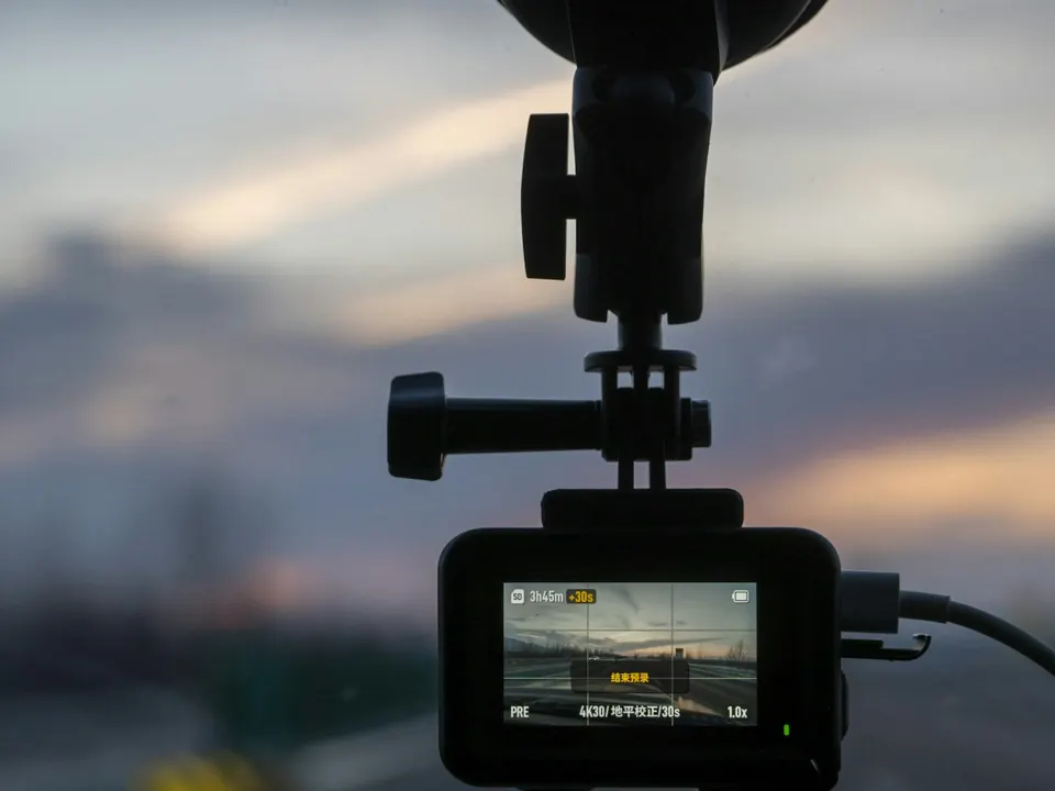 Compact camera mounted inside a vehicle, with the road visible on its screen