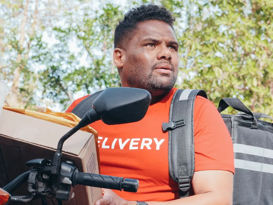 Delivery worker with parcels beside a motor scooter