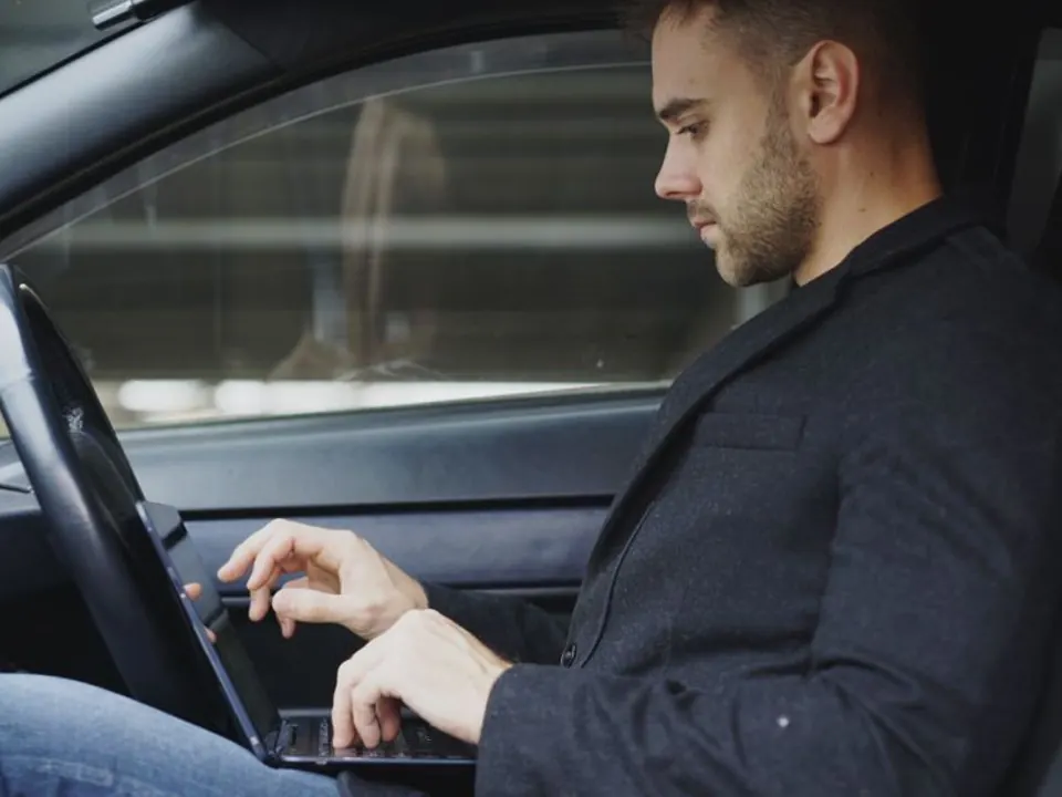 Fleet operator using a laptop while seated in a stationary car